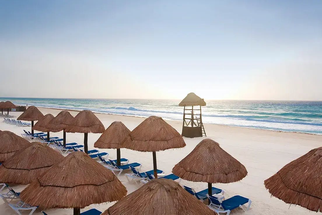 Cancun-beach-during-daytime-with-lounge-chairs-umbrellas